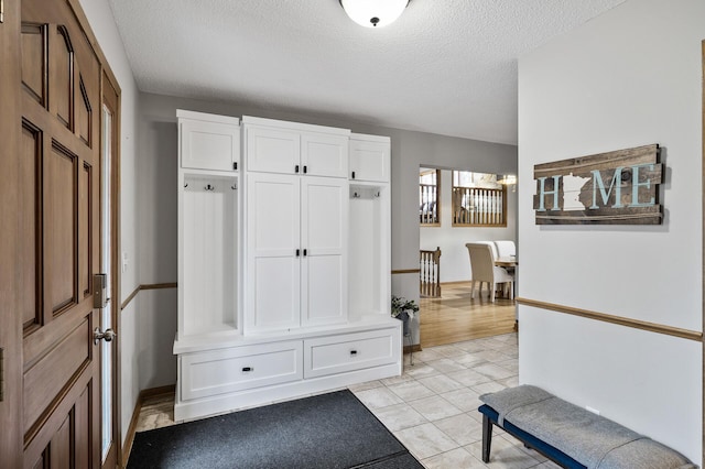 mudroom featuring a textured ceiling and baseboards