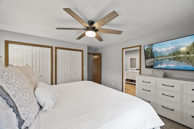 bedroom featuring a textured ceiling, two closets, a ceiling fan, and ensuite bathroom