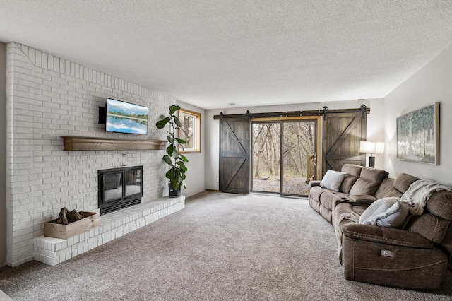 living area with a brick fireplace, a textured ceiling, a barn door, and carpet floors