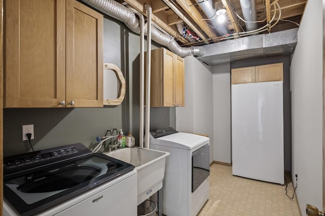 laundry area with light floors, a sink, cabinet space, and washing machine and dryer