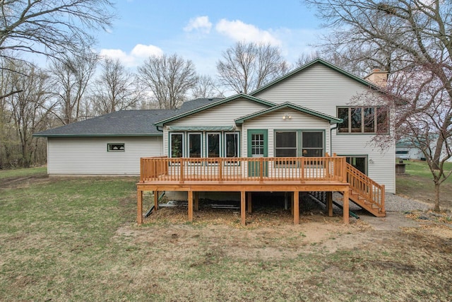 back of property featuring stairs, a wooden deck, a chimney, a lawn, and a sunroom
