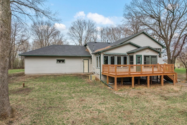 rear view of property featuring a wooden deck, a shingled roof, and a lawn