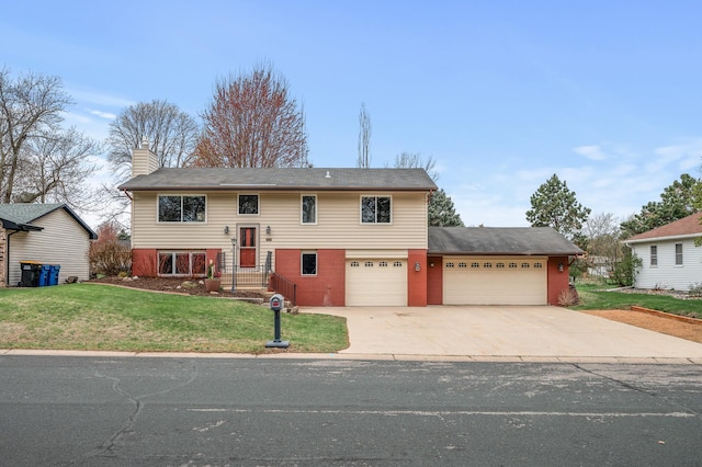 bi-level home with driveway, a chimney, a front yard, a garage, and brick siding