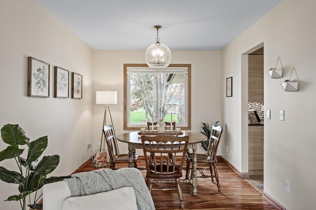 dining room with an inviting chandelier, baseboards, and wood finished floors