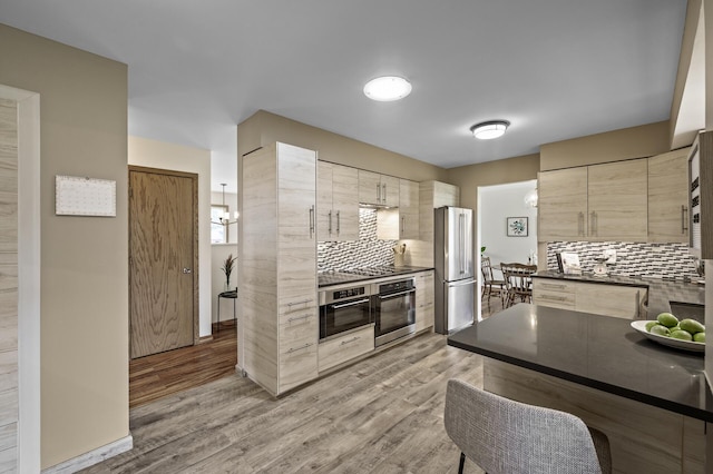 kitchen with dark countertops, tasteful backsplash, modern cabinets, light wood-type flooring, and stainless steel appliances