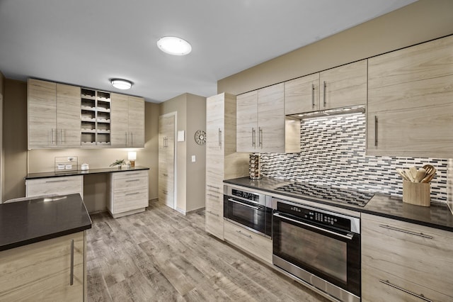 kitchen with stovetop, dark countertops, modern cabinets, light brown cabinets, and stainless steel oven