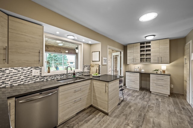 kitchen featuring light brown cabinetry, dark countertops, a sink, light wood finished floors, and dishwasher