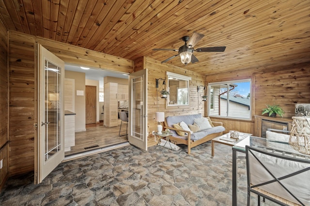 interior space with french doors, stone flooring, wood ceiling, and wooden walls