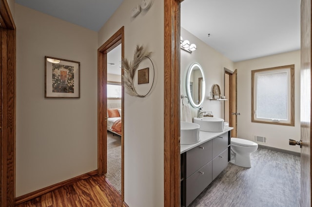 bathroom featuring vanity, toilet, baseboards, wood finished floors, and visible vents
