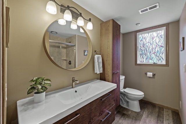 bathroom featuring vanity, toilet, wood finished floors, visible vents, and a stall shower