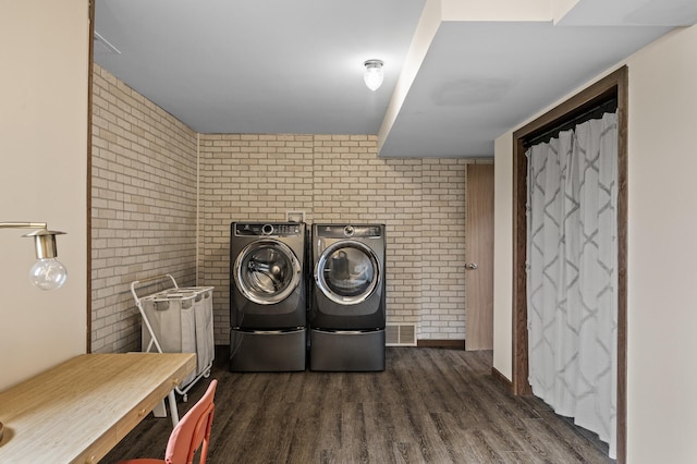 laundry room with laundry area, visible vents, wood finished floors, washer and dryer, and brick wall