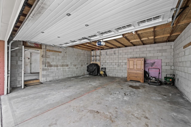 garage featuring concrete block wall and a garage door opener