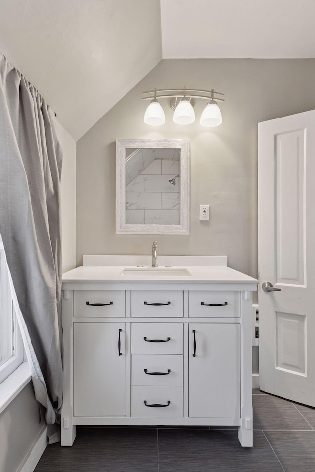 bathroom with vanity, vaulted ceiling, and baseboards