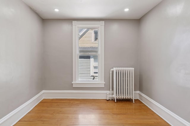 empty room featuring radiator heating unit, light wood-style floors, recessed lighting, and baseboards