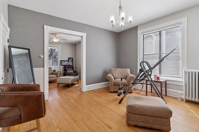 living area featuring baseboards, radiator, a notable chandelier, and light wood finished floors
