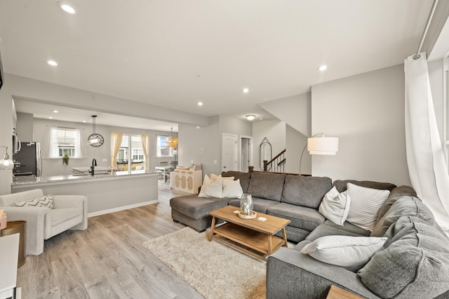 living room with recessed lighting, light wood-type flooring, and stairs
