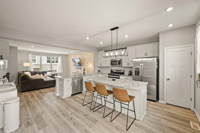 kitchen with recessed lighting, a peninsula, a breakfast bar area, appliances with stainless steel finishes, and a sink
