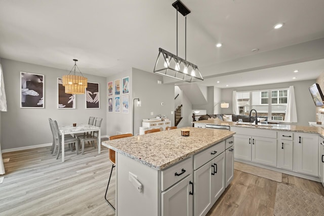 kitchen with a center island, an inviting chandelier, a sink, open floor plan, and light wood-style flooring