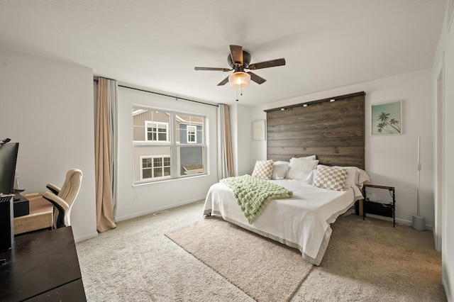 bedroom featuring visible vents, baseboards, ceiling fan, and light carpet