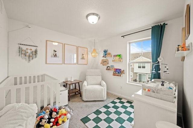 bedroom featuring a crib, baseboards, and carpet floors