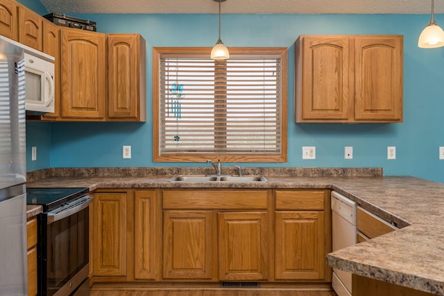 kitchen with hanging light fixtures, visible vents, a sink, dark countertops, and stainless steel appliances