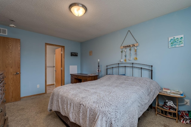 bedroom featuring carpet, visible vents, a textured ceiling, and baseboards