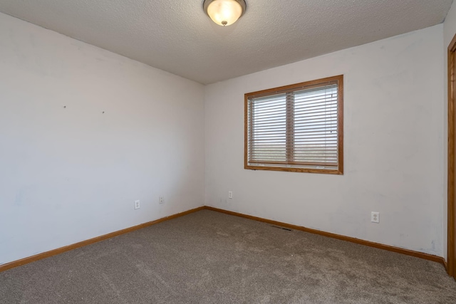 unfurnished room with carpet floors, baseboards, visible vents, and a textured ceiling