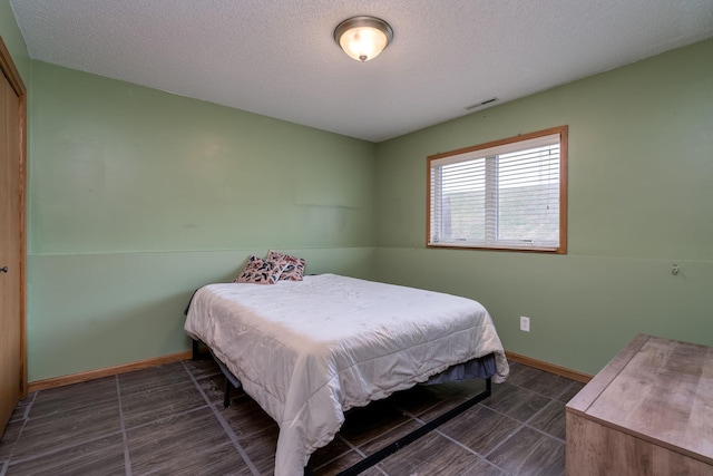 bedroom featuring visible vents, baseboards, and a textured ceiling