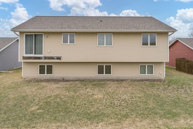 back of property featuring a yard, fence, and roof with shingles