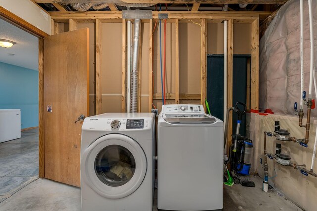 clothes washing area featuring separate washer and dryer and laundry area