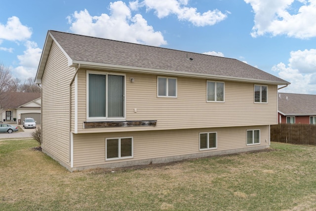 rear view of house featuring fence and a lawn