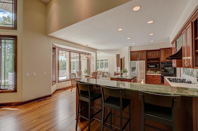 926 Kohlman Ln, Maplewood, MN 55109 - kitchen featuring black appliances, wall chimney exhaust hood, a peninsula, recessed lighting, and light wood-type flooring