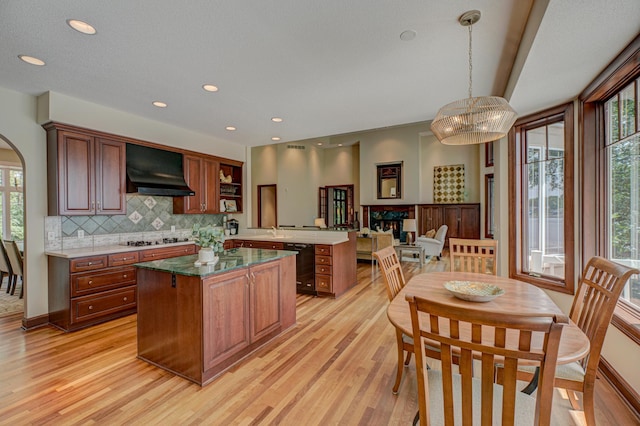926 Kohlman Ln, Maplewood, MN 55109 - kitchen with wall chimney range hood, a peninsula, light wood-style flooring, gas cooktop, and decorative backsplash