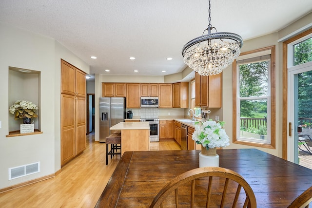 17299 66th Pl N, Maple Grove, MN 55311 - kitchen with stainless steel appliances, a chandelier, light wood-style floors, light countertops, and a center island