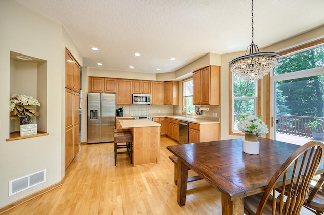 17299 66th Pl N, Maple Grove, MN 55311 - kitchen featuring appliances with stainless steel finishes, light wood-style floors, light countertops, a chandelier, and a kitchen island