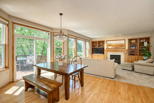 17299 66th Pl N, Maple Grove, MN 55311 - dining room with a textured ceiling, a chandelier, light wood-style flooring, a tile fireplace, and built in features