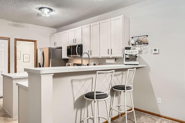 13397 Europa Ct N Unit 5, Hugo, MN 55038 - kitchen featuring stainless steel appliances, a peninsula, a breakfast bar area, tasteful backsplash, and light countertops