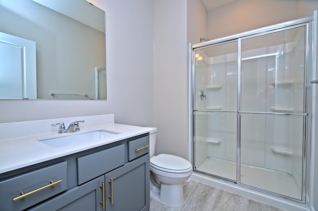 bathroom with toilet, a shower stall, vanity, and wood finished floors