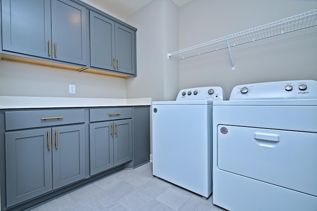 washroom with washer and clothes dryer, light floors, and cabinet space