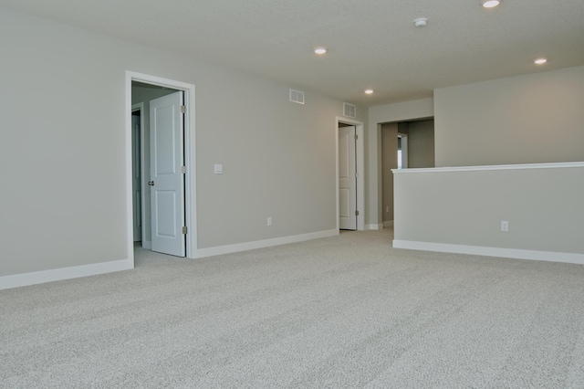 spare room featuring light colored carpet, baseboards, visible vents, and recessed lighting