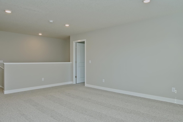 spare room featuring recessed lighting, light colored carpet, and baseboards