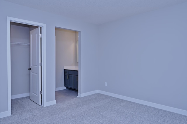 unfurnished bedroom featuring a closet, light colored carpet, baseboards, and a spacious closet