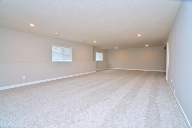 spare room with baseboards, recessed lighting, and light colored carpet