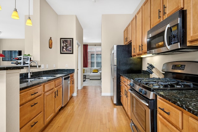 831 River Mews Ct, Minneapolis, MN 55414 - kitchen featuring stainless steel appliances, dark stone countertops, light wood-style flooring, decorative light fixtures, and a peninsula