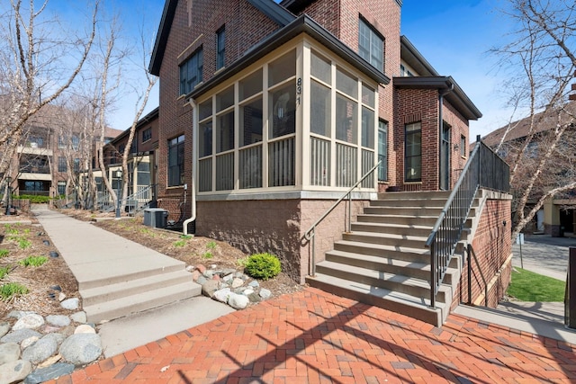 831 River Mews Ct, Minneapolis, MN 55414 - view of side of home with brick siding, stairway, and a sunroom