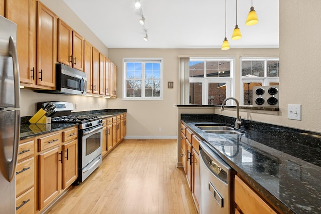 831 River Mews Ct, Minneapolis, MN 55414 - kitchen featuring appliances with stainless steel finishes, light wood-style flooring, hanging light fixtures, and dark stone counters