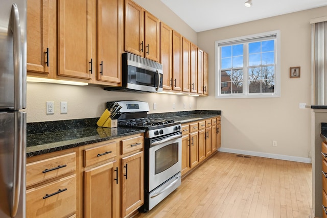 831 River Mews Ct, Minneapolis, MN 55414 - kitchen featuring stainless steel appliances, dark stone counters, and light wood-style floors