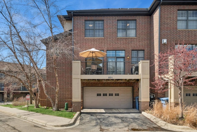 831 River Mews Ct, Minneapolis, MN 55414 - townhome / multi-family property featuring driveway, a balcony, brick siding, and an attached garage