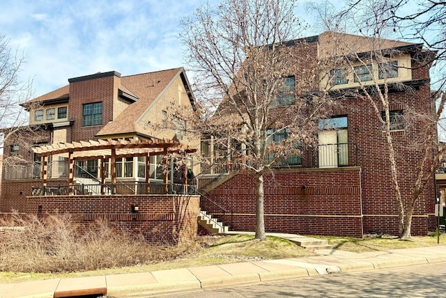 831 River Mews Ct, Minneapolis, MN 55414 - tudor-style house featuring a pergola, brick siding, and roof with shingles