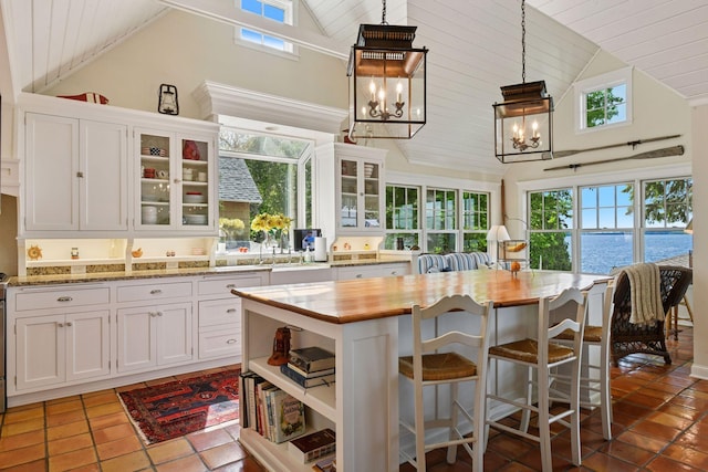 19820 Lakeview Ave, Deephaven, MN 55331 - kitchen featuring high vaulted ceiling, wood ceiling, a chandelier, white cabinets, and decorative light fixtures